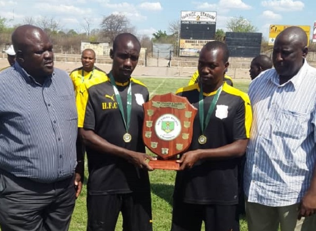 Hwange captains Obert Moyo (left ) and Gerald Ndlovu pose with the championship shield flanked by Zifa Southern Region chairman Andrew Tapela (right) and board member Fiso Siziba.